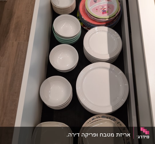 צלחות וקערות מסודרות במגירה במטבח